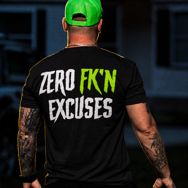 A man viewed from behind wearing a black t-shirt with the text 'ZERO FK'N EXCUSES' printed on the back in white and neon green, paired with a bright green cap.
