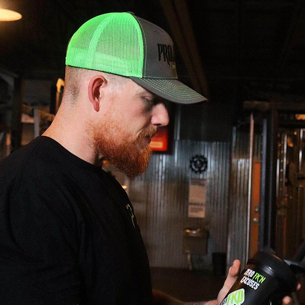 Gym guy wearing green Project Z hat while holding a metal blender bottle. 