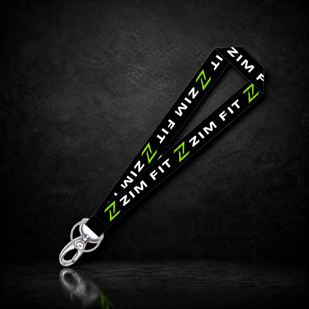 A black  keychain with repeating white 'ZIM FIT' text and bright green 'ZIM' logos, attached to a silver metal lobster clasp, displayed on a dark textured background.